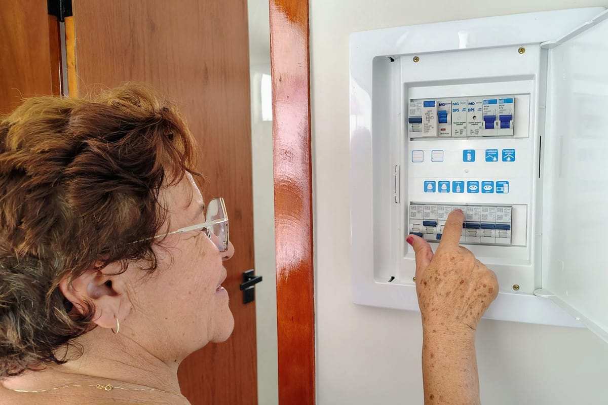 Moteris spaudžia mygtuką atidarytame elektros skyde su moduliniais įrenginiais